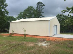 A metal building with a white roof in the middle of a field.
