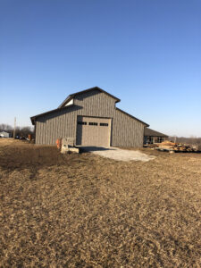 A barn with a metal roof in the middle of a field.