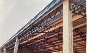 An old photo of a barn with wooden beams and metal building elements.