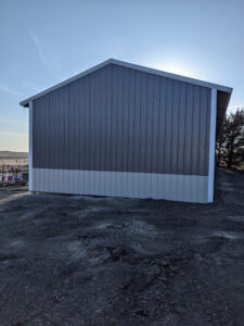 A gray and white barn with a blue roof.