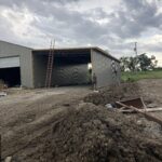 A building under construction in a dirt field.