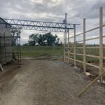A wooden fence is being built on a dirt road.