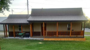 A small house with a wooden porch and a metal roof.