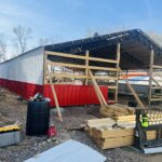 A red and white barn being built in a yard.