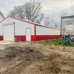 A red and white barn with a dirt floor.