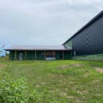 A building with a green roof and black siding.