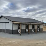 A black and white horse barn with a white roof.