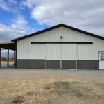 A white and black barn with a door in the middle.