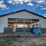 A barn under construction with a crane in the background.