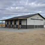 A horse barn in the middle of a field.