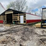 A red and white barn is being built in a field.